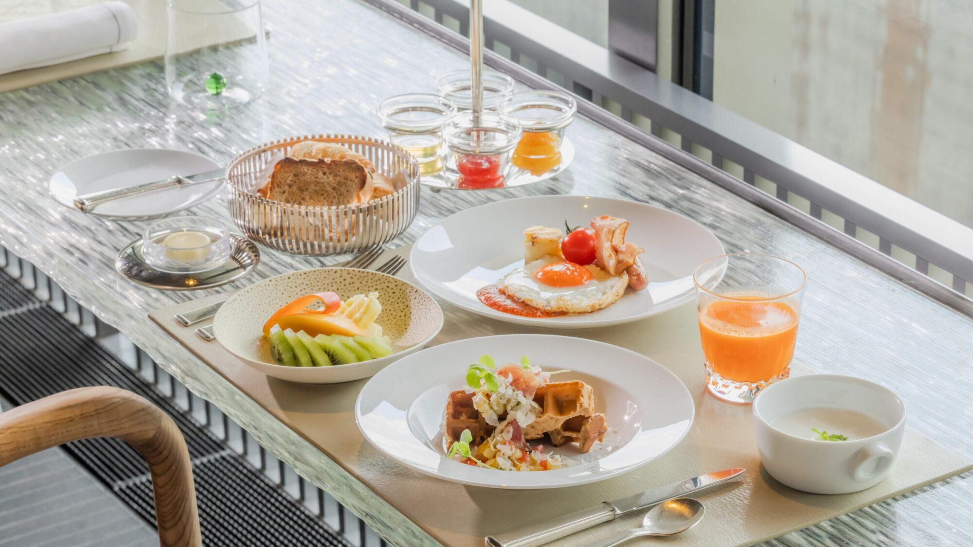 自家製パンやフレッシュジュース、ローストビーフサラダ、季節のフルーツなどが並ぶ、ホテルの朝食セット。